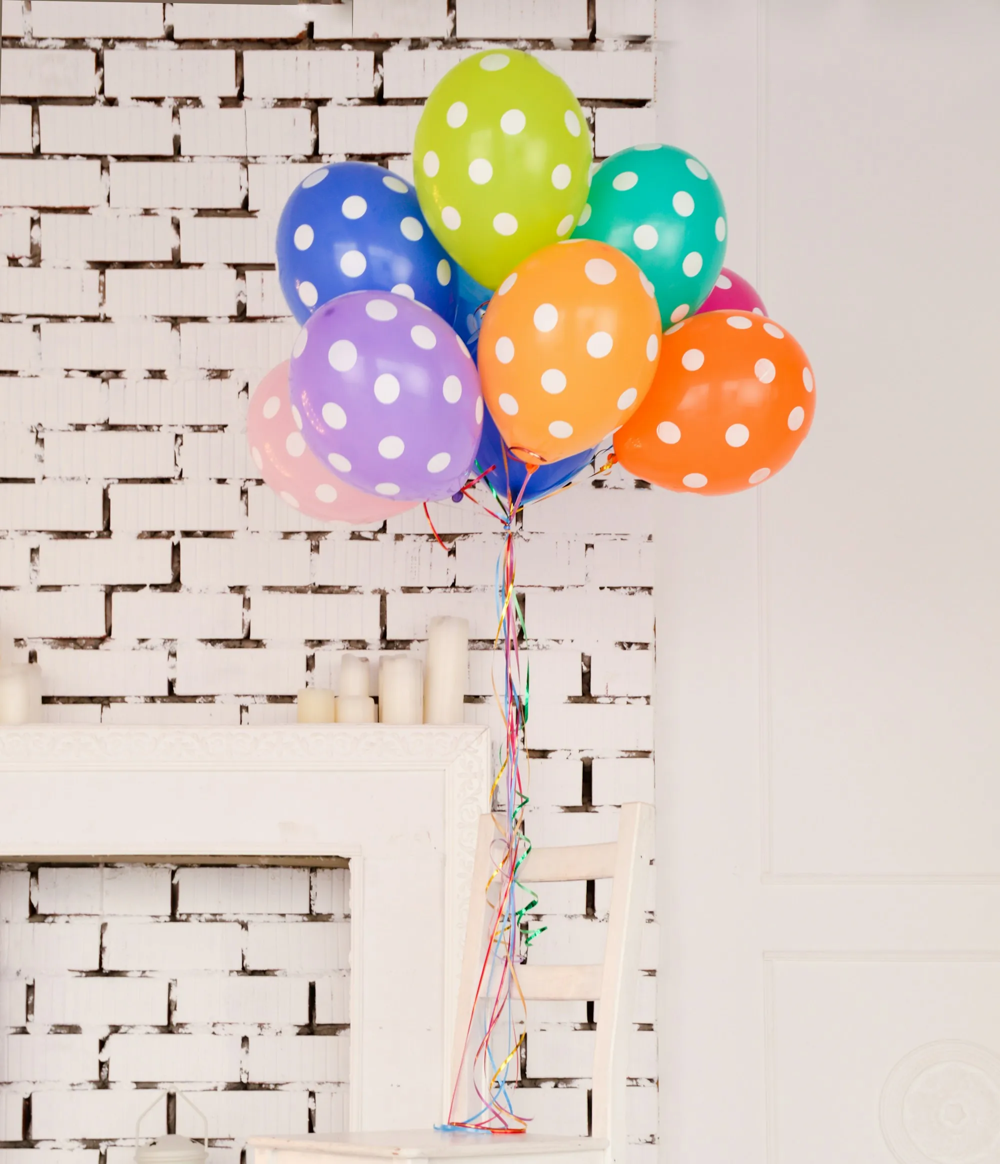 Polka-dot balloon bouquet beside a fireplace