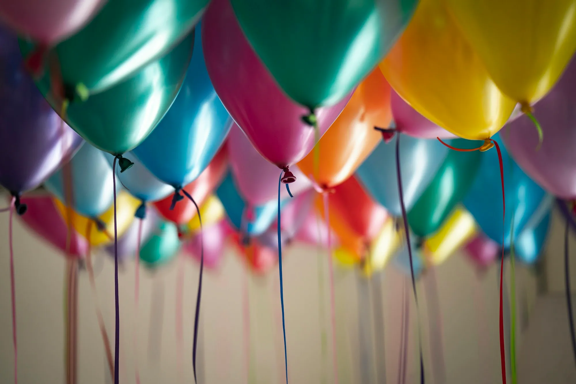Ceiling covered with jewel-tone metallic balloons and hanging ribbons