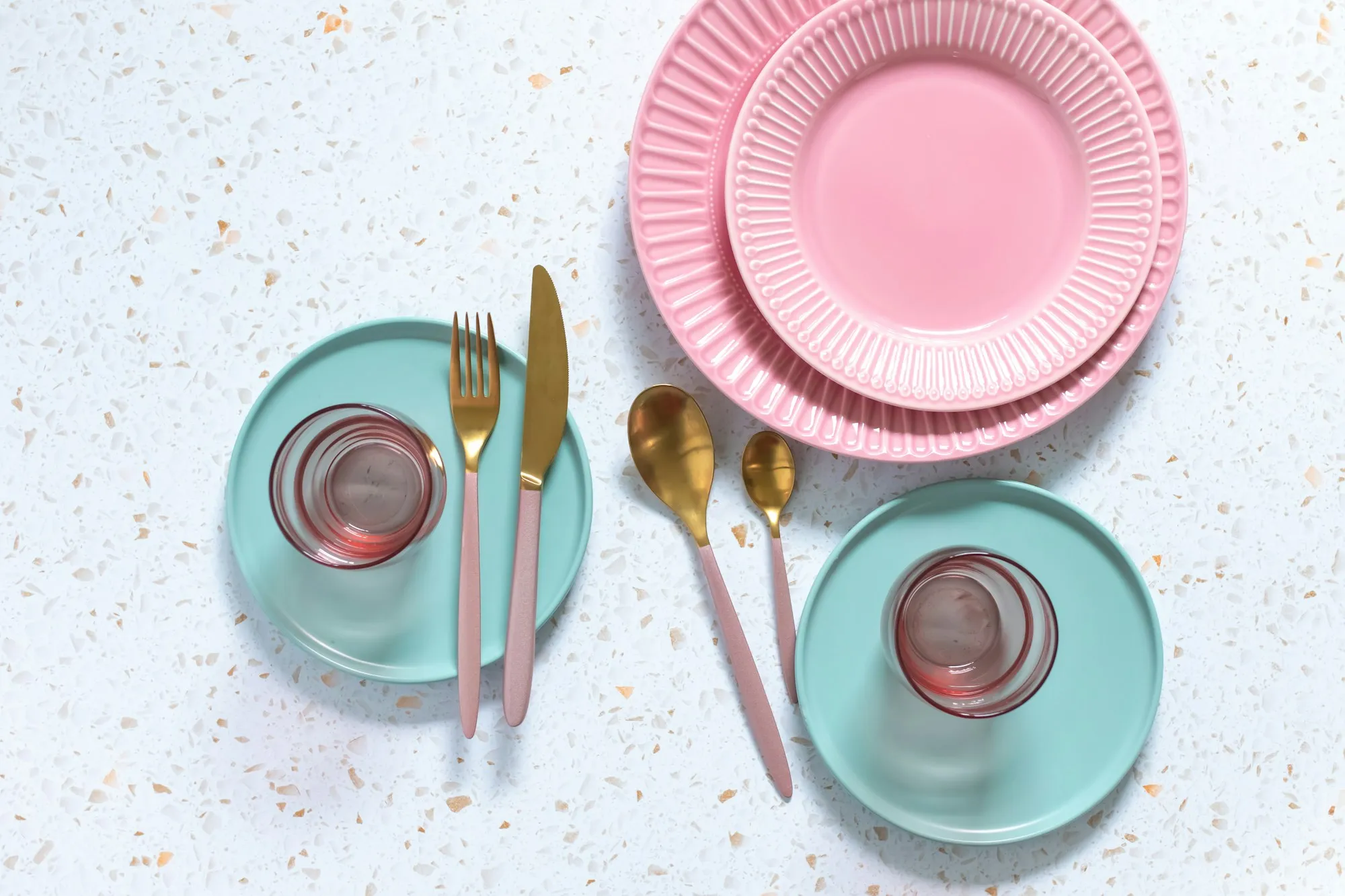 Pink and mint paper plates with gold cutlery on a party table