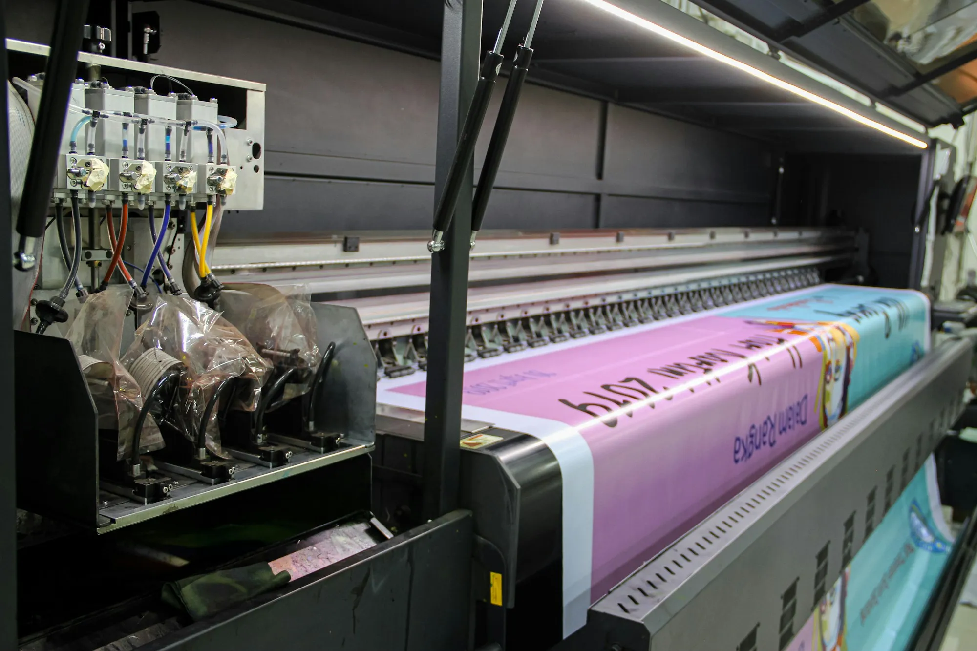 Wide-format printer printing a pink vinyl banner
