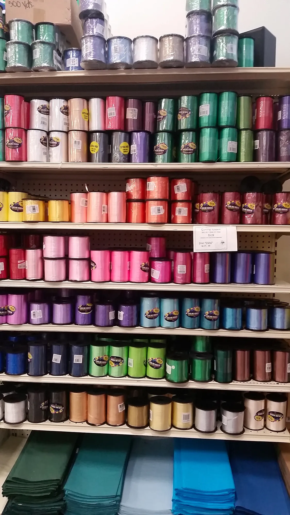 Floor-to-ceiling wall of ribbon spools in many colors